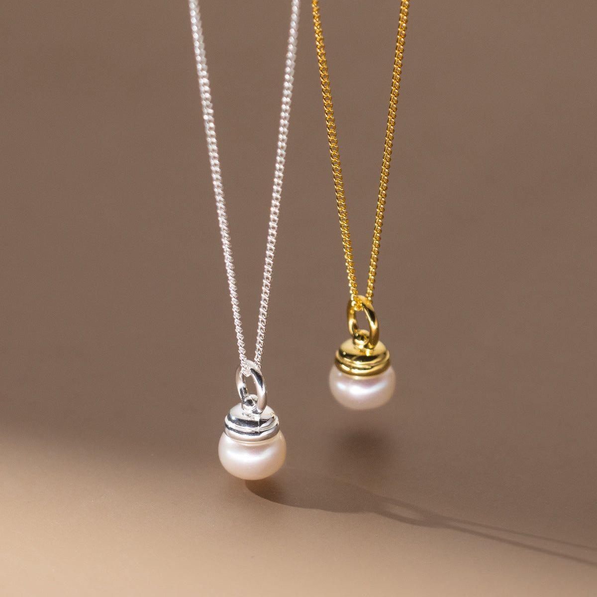 A pair of 925 sterling silver single pearl vintage necklaces, one in a silver finish and the other in a gold finish, displayed on a neutral background.