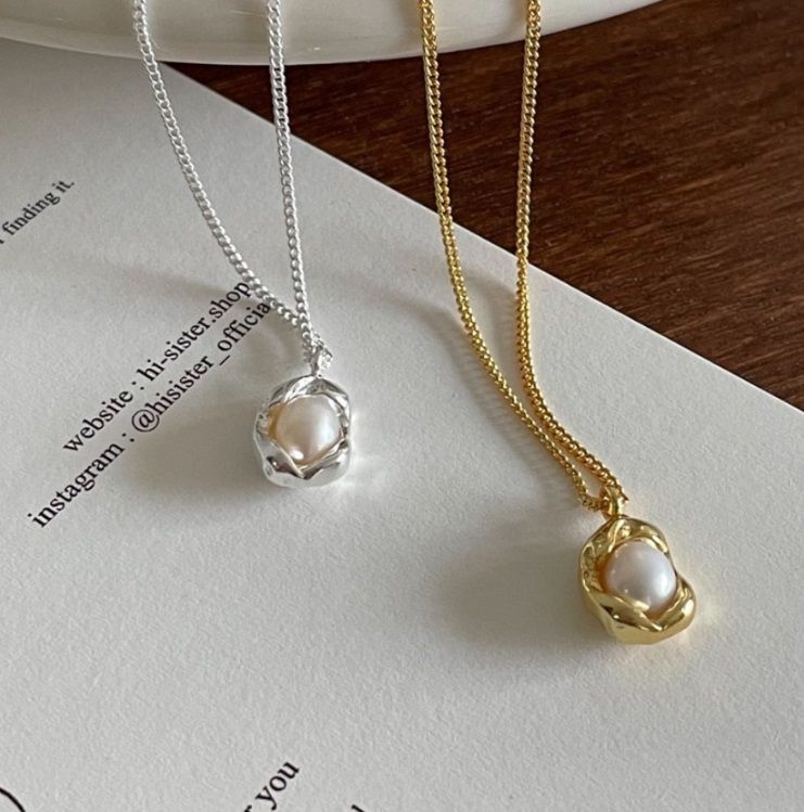 Un par de elegantes collares de perlas de plata esterlina 925, uno bañado en oro y el otro en plata, exhibidos sobre un fondo neutro para resaltar su diseño clásico.