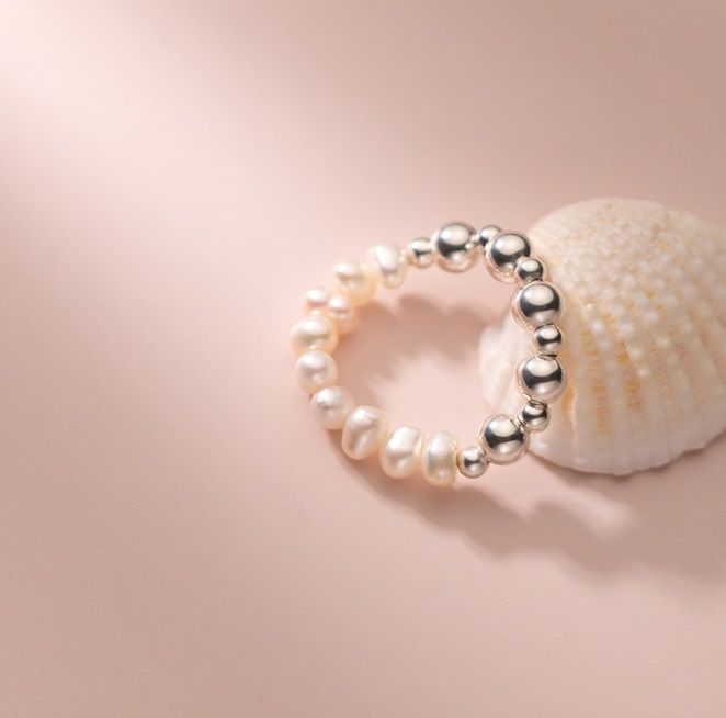 Una vista ravvicinata dell'anello elastico in argento sterling 925 con perle d'acqua dolce, che mette in mostra le sue perle lucenti e i dettagli delle perle d'argento.