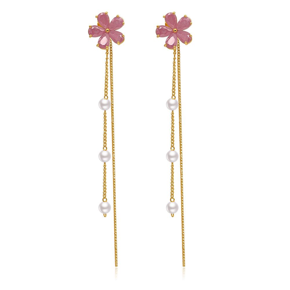 Un gros plan des boucles d'oreilles pendantes Pearl Blossomed, mettant en valeur les têtes en forme de fleur rose et les délicates chaînes en or avec des perles blanches.