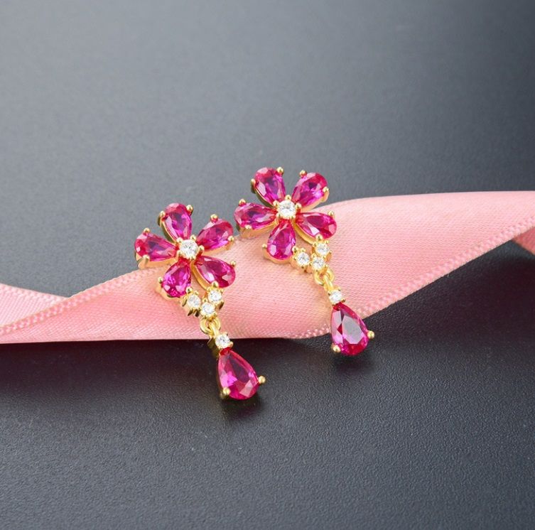 Un paio di orecchini Dainty Flower in argento sterling 925 con placcatura in oro, caratterizzati da punte a forma di fiore con pietre di zirconia cubica rosa e bianche e gemme rosa a forma di goccia pendenti.