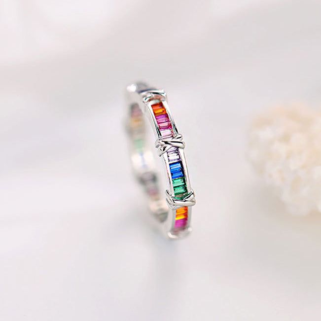 Un primer plano de un anillo de plata esterlina 925 del conjunto de cruz de zirconia arcoíris, mostrando las vibrantes piedras de zirconia multicolores incrustadas en la banda.
