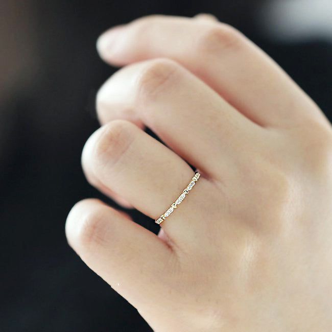Un modèle portant le set de bagues fines en argent sterling 925 plaquées or en forme de cœur et en zircon, montrant comment les cinq bagues peuvent être empilées.