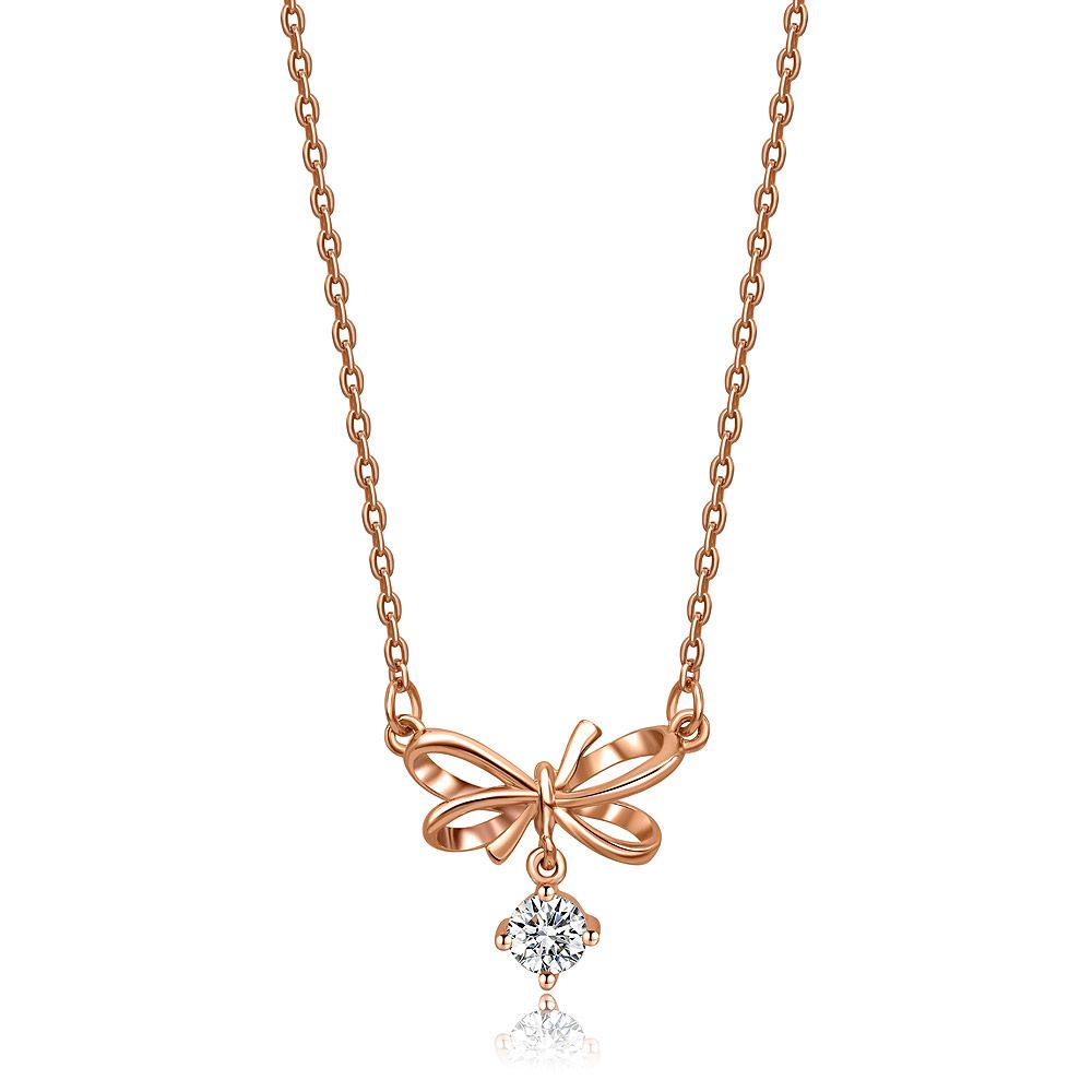 Eine zarte, roségoldplattierte Halskette mit einem schleifenförmigen Anhänger und einem zentralen Zirkonia-Diamanten, auf einem weißen Hintergrund präsentiert.