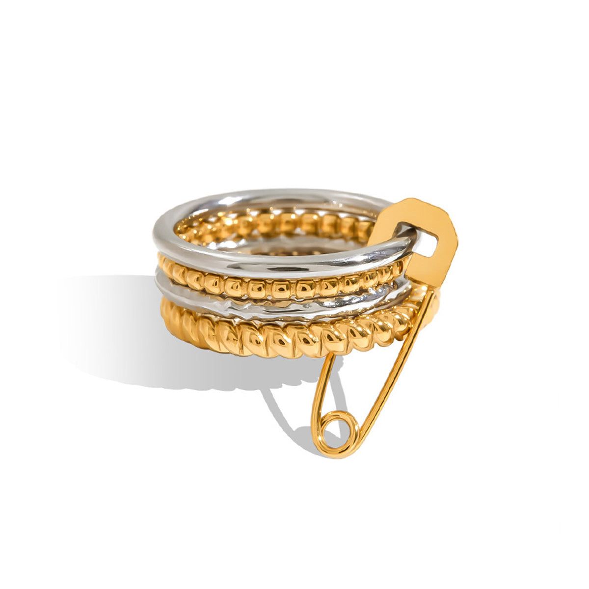 Um close-up de um conjunto único de anéis empilháveis com um design em ouro e prata, apresentando um charme de alfinete de segurança proeminente, feito de aço inoxidável que não mancha.
