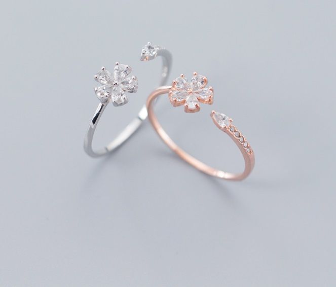 Un par de anillos de flor de plata esterlina 925, uno en plata y otro en oro rosa, ambos con intrincados diseños florales con piedras de circonita cúbica brillantes.
