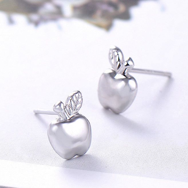 Un paio di orecchini a bottone a forma di mela in argento sterling 925 carini con dettagli delicati delle foglie, mostrati su uno sfondo bianco.