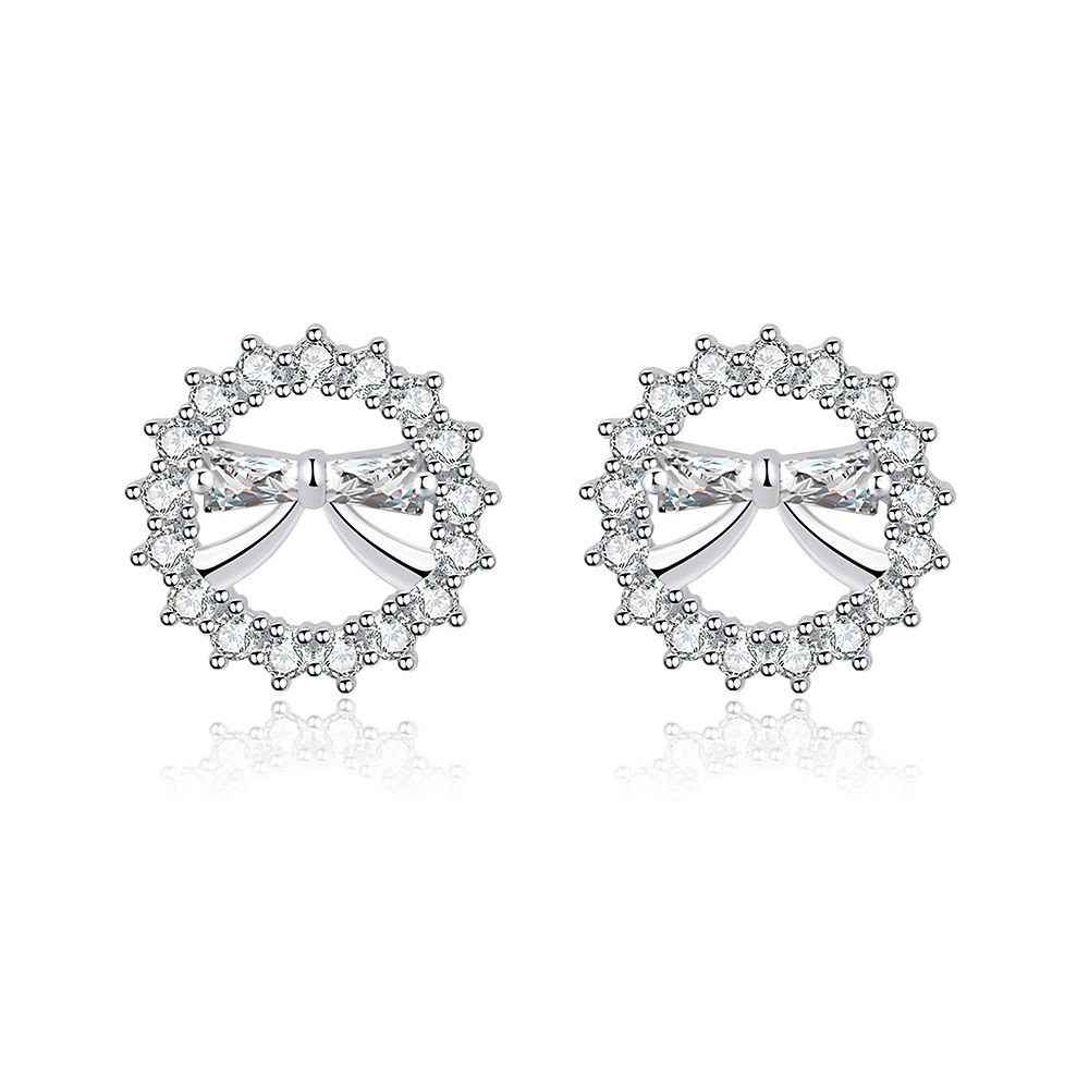 Une paire de boucles d'oreilles en forme de nœud mini rond, avec un centre en argent entouré de zircon cubique blanc étincelant dans un motif floral, sur un fond blanc.