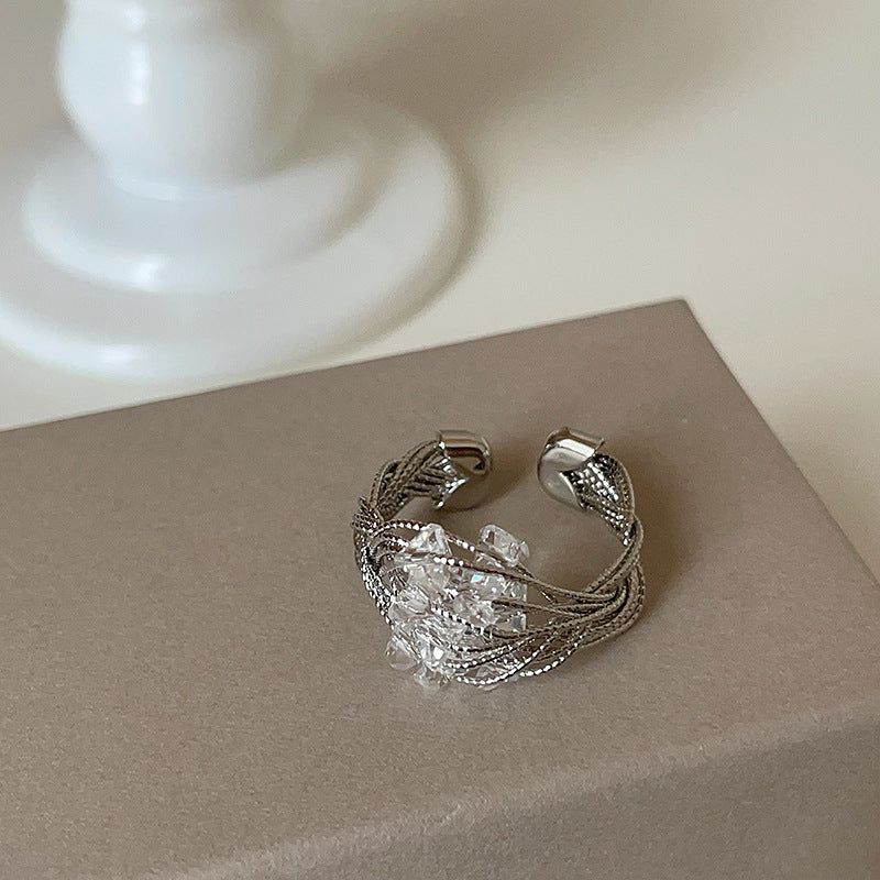 A silver-tone adjustable ring with an intricate wire-wrapped design and a sparkling crystal centerpiece, displayed on a neutral background.