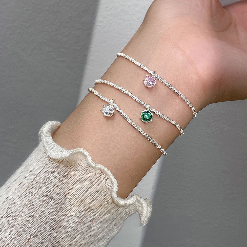 Ein Set aus drei 925er Sterlingsilberarmbändern mit funkelnden Zirkonsteinen in Weiß, Rosa und Grün, auf einem neutralen Hintergrund präsentiert.