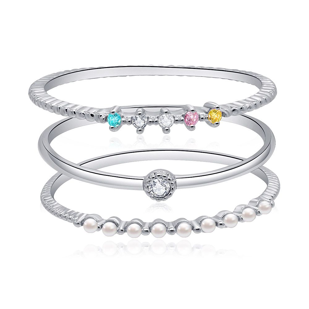 A set of three ultra-thin stackable band rings with multi-colored cubic zirconia stones, displayed on a neutral background.
