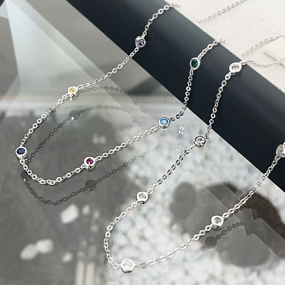 Une collection de colliers en chaîne en argent sterling 925 en gros, chacun présentant un charm en pierre CZ multicolore vibrant de 4 mm, exposés élégamment.