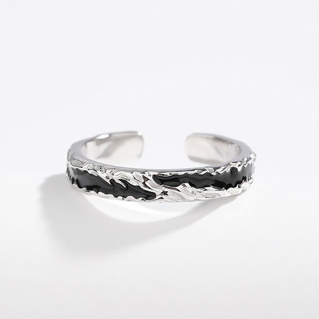 Un primo piano di un anello aperto in argento sterling 925 per uomini con un'inserzione distintiva in smalto nero e un design ondulato moderno.