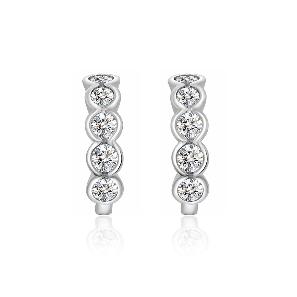 Une paire de boucles d'oreilles mini huggie en laiton plaqué rhodium, chacune présentant quatre pierres en zircon cubique brillantes, serties en chaton, sur un fond blanc.