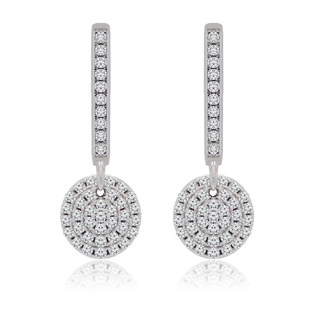 Un gros plan des boucles d'oreilles pendantes en disque rond, mettant en valeur le laiton plaqué rhodium et le motif en spirale complexe des pierres en zircon cubique étincelantes sur le pendentif circulaire.
