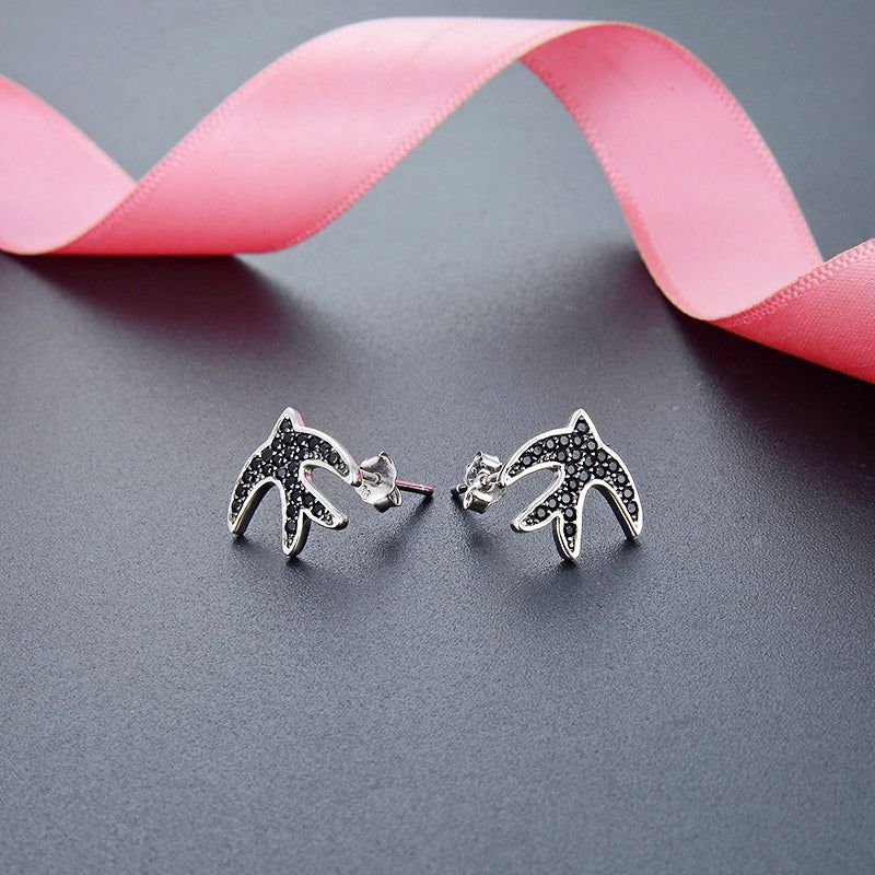 A pair of 925 sterling silver swallow bird stud earrings, intricately designed with sparkling black zircon stones, displayed on a white background.