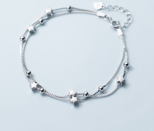 Eine Nahaufnahme des 925 Sterling Silber Sternarmbands, das sein doppelt-strängiges Design mit zarten Stern- und Kugelanhängern zeigt.