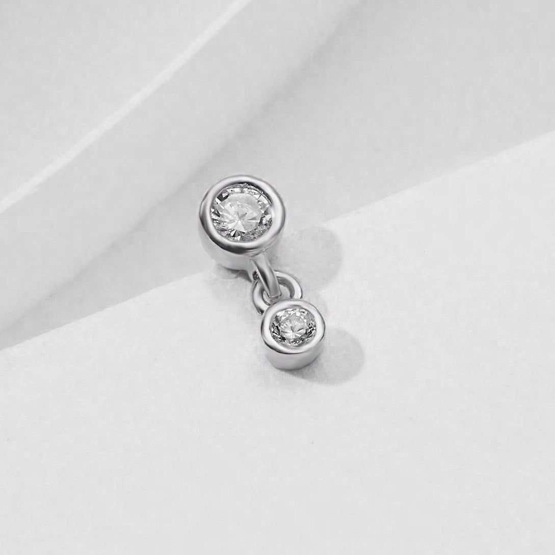 Un paio di orecchini a perno in argento sterling 925, ciascuno con due pietre rotonde bianche in zirconia cubica in una montatura verticale pulita e contemporanea.