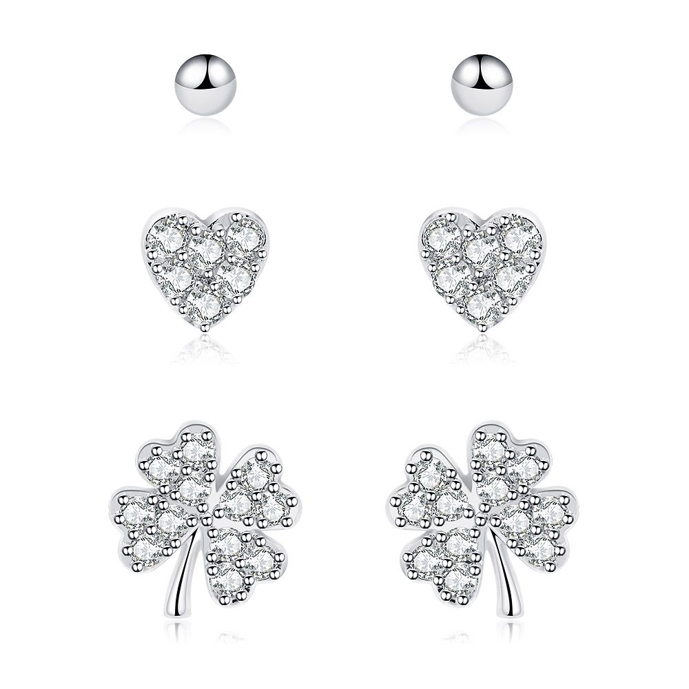 A set of three rhodium-plated stud earrings featuring a tiny heart, a ball bead, and a clover leaf, all with sparkling cubic zirconia accents.