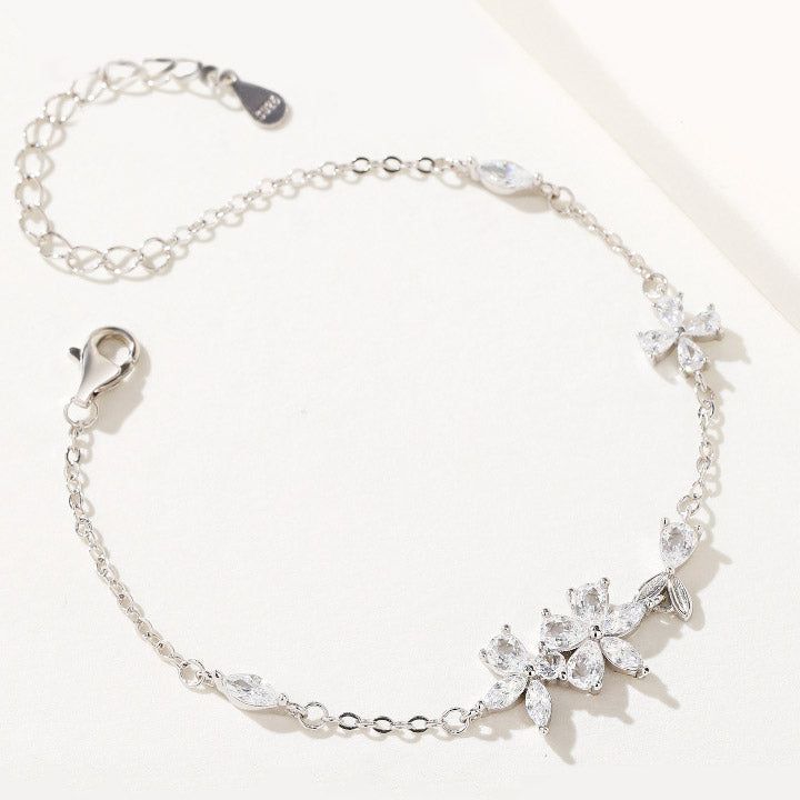 Un primo piano di un bracciale a fiore di sakura in argento sterling 925 del set, che mostra il design floreale intricato con pietre di zirconia trasparente scintillanti.