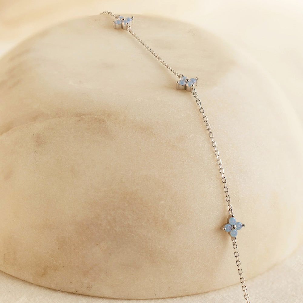 Primer plano de la pulsera Lucky Clover de plata esterlina 925, mostrando los delicados charms de flores con piedras de zirconia azul claro.