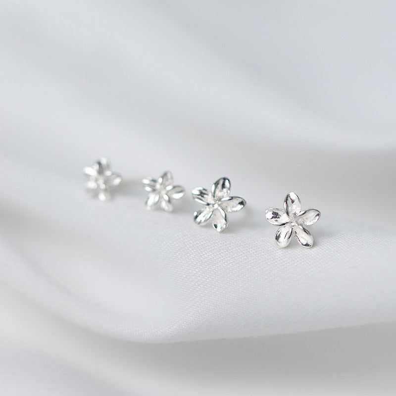 Een set van drie S925 sterling zilveren kleine bloemen stud oorbellen weergegeven op een gestructureerde witte achtergrond, met de nadruk op hun delicate bloemontwerp.