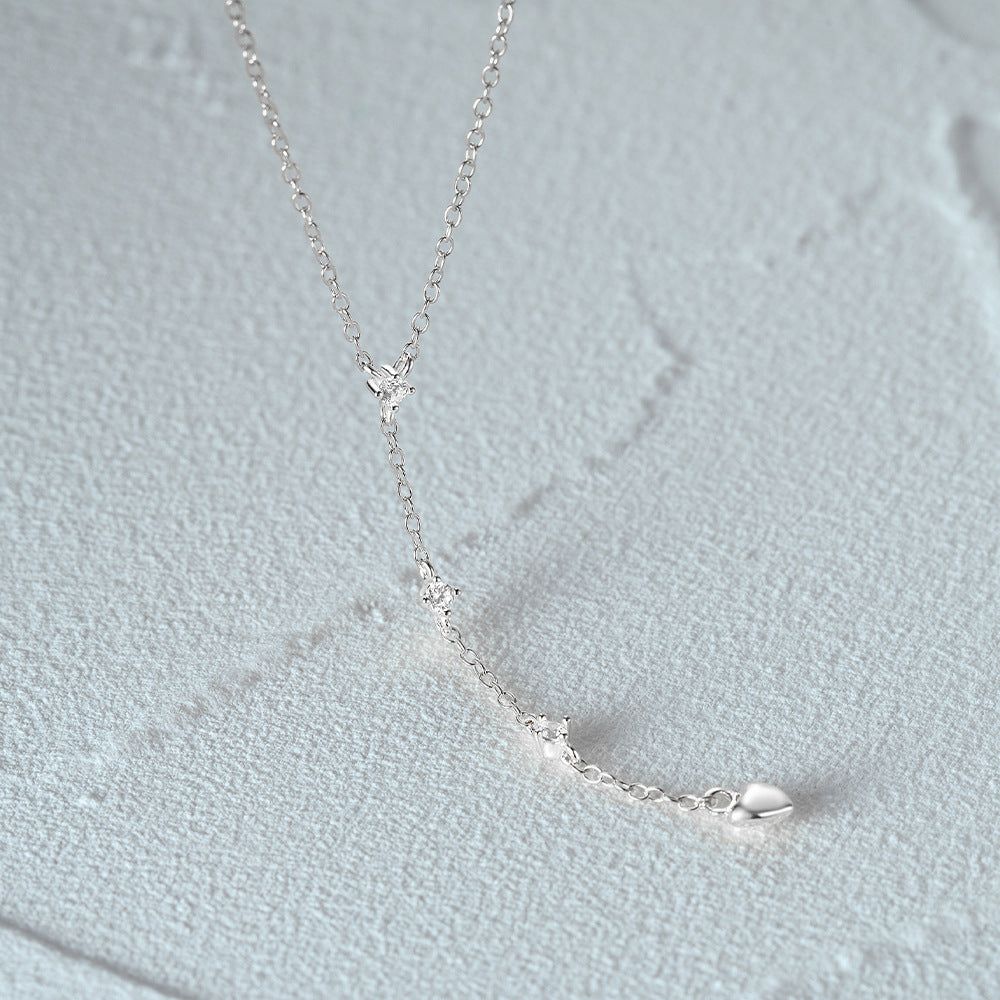 Un primer plano del collar en forma de Y de plata esterlina 925, destacando su diseño minimalista y su distintivo cierre en forma de corazón.