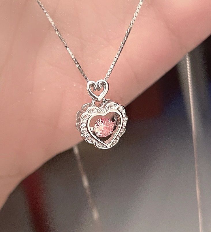 Close-up of a 925 sterling silver open heart necklace featuring a central dancing pink cubic zirconia gemstone.