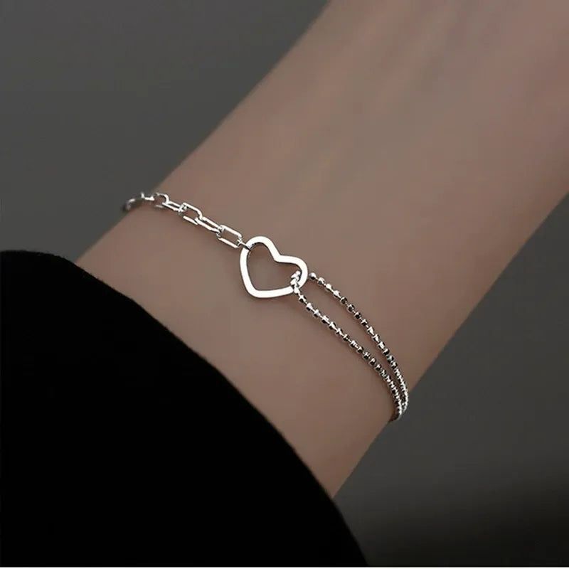 Une femme portant le bracelet cœur ouvert minimaliste en argent sterling 925, mettant en avant son délicat design à double chaîne.