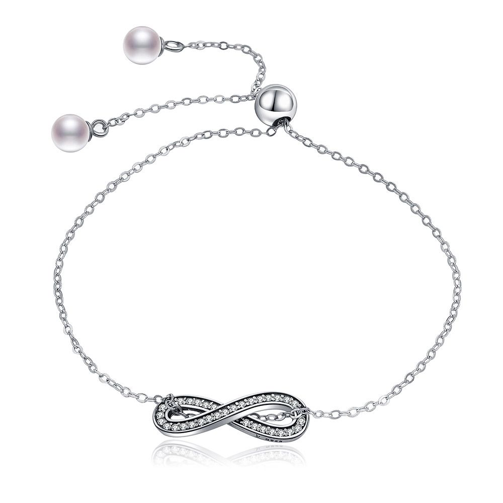 Elegant sterling silver infinity pave bracelet featuring a sparkling cubic zirconia centerpiece and a delicate pearl on the adjustable clasp.