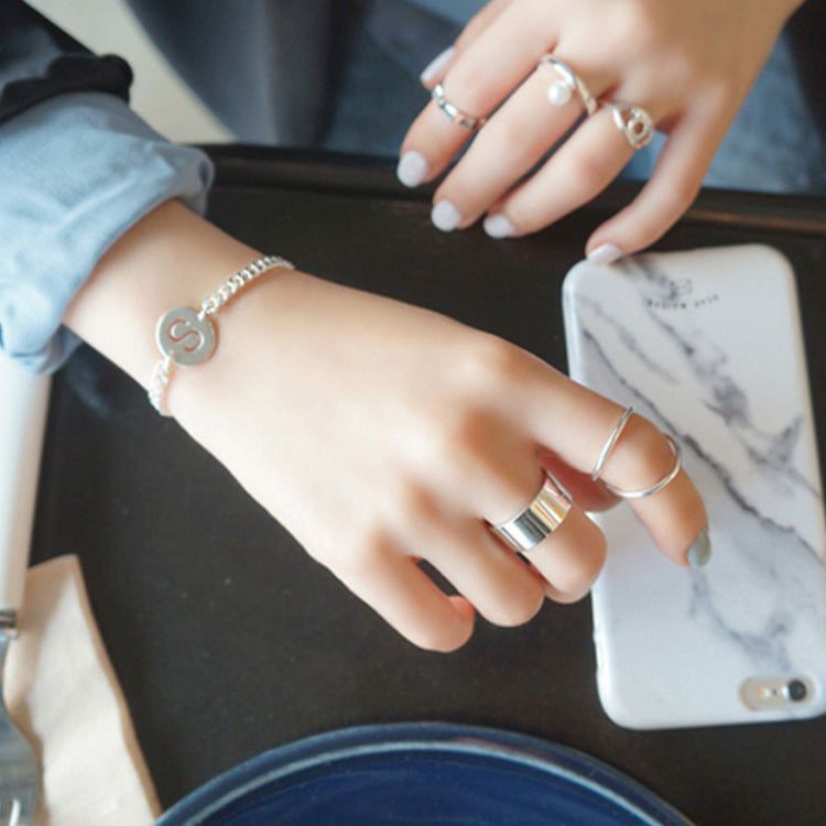 Les mains d'une femme portant une pile de bagues larges en argent sterling 925 minimalistes, présentant un look tendance de style coréen pour les bijoux en gros.