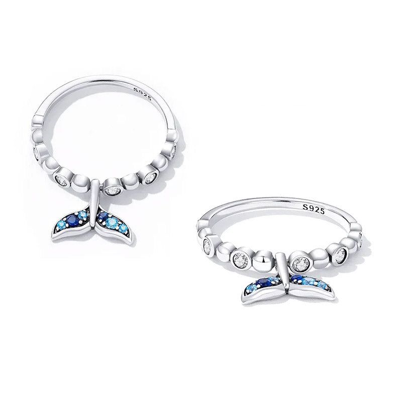 Gros plan de deux bagues ajustables en argent sterling 925 avec un design détaillé de queue de sirène et des pierres en zircon cubique bleues et transparentes.