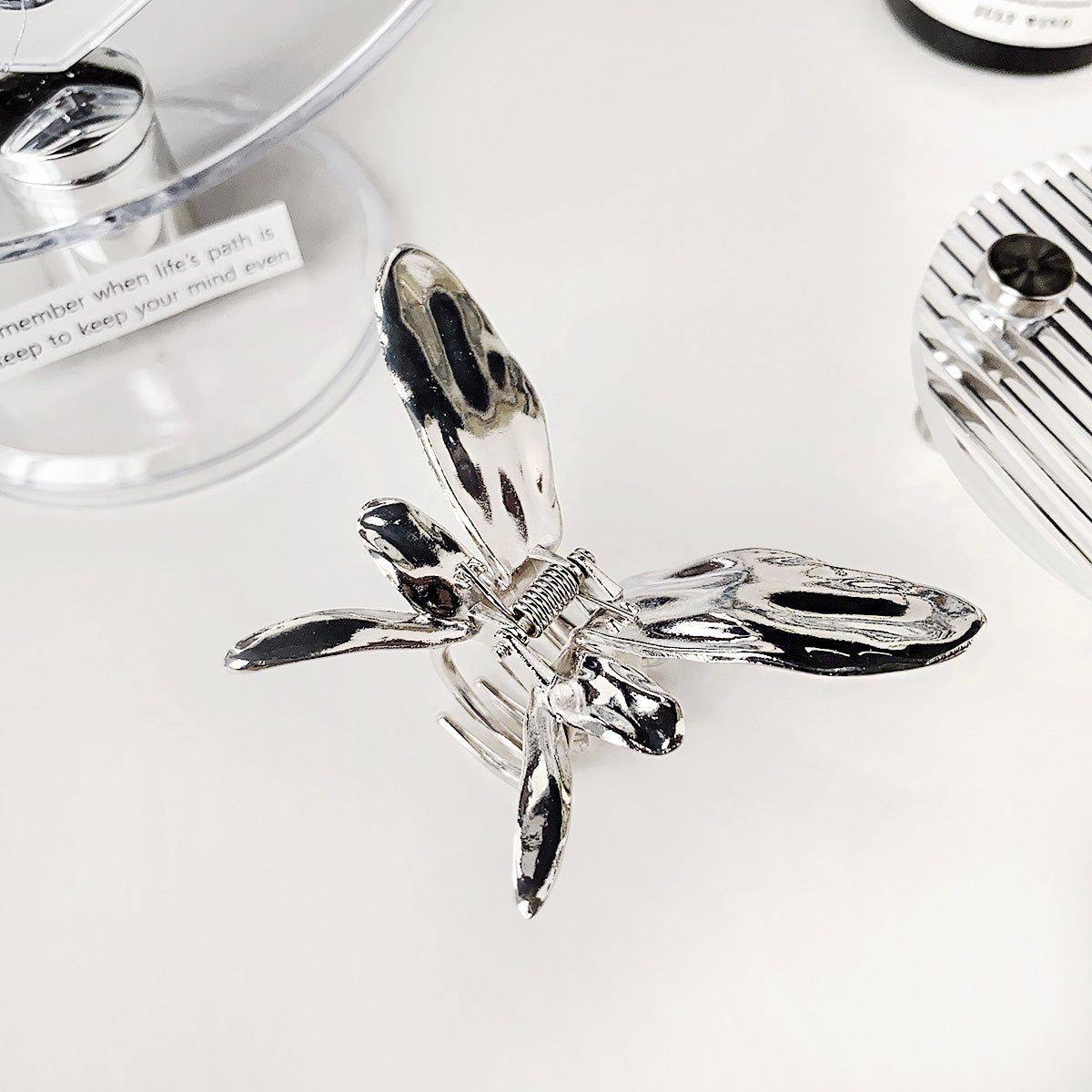 A detailed close-up of a shiny silver metal butterfly hair claw clip, showcasing its intricate wing design and durable construction.