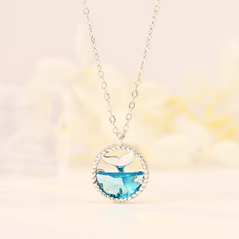 A delicate 925 sterling silver necklace featuring an elegant mermaid tears whale tail pendant with a blue gemstone, displayed on a neutral background.