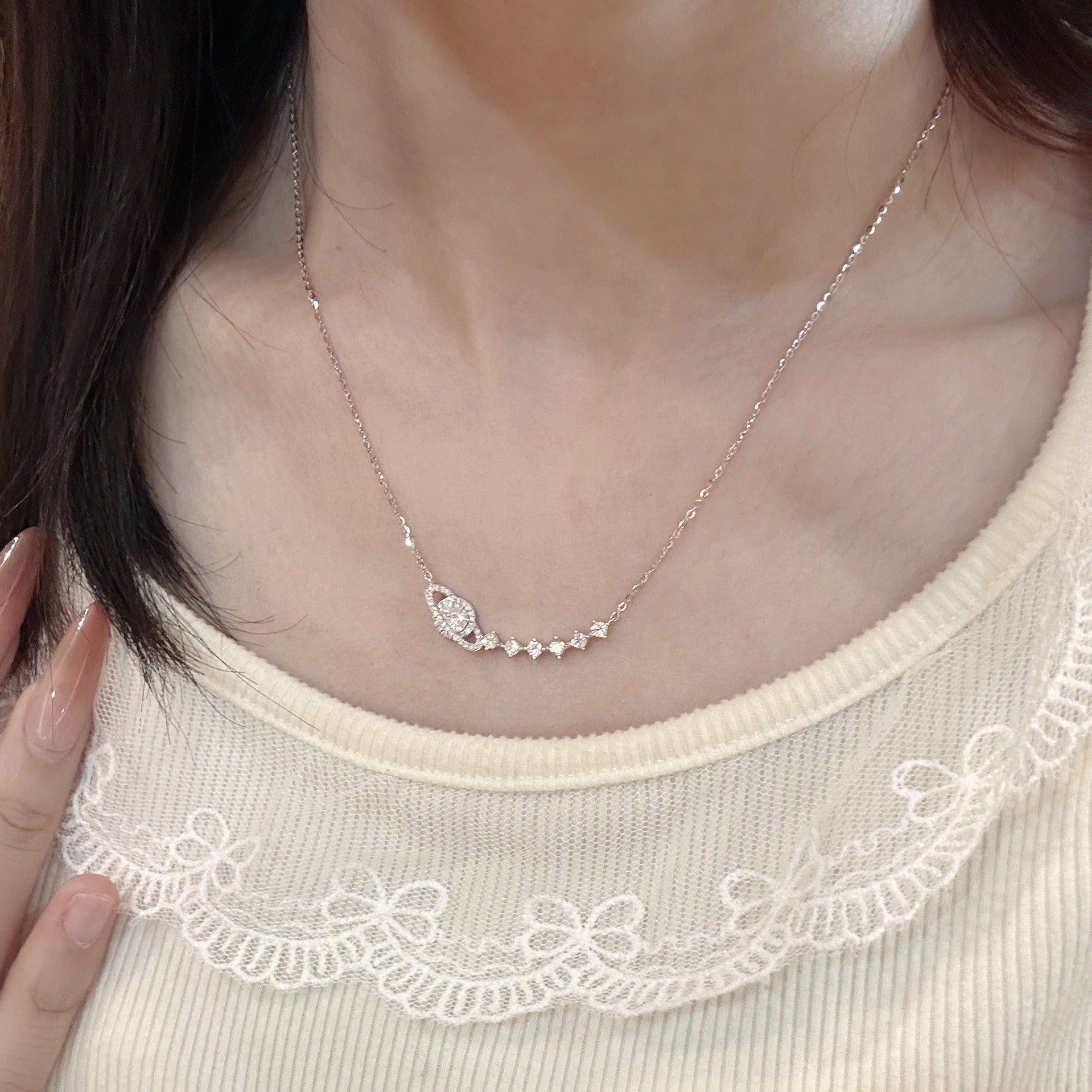 A model wearing the 925 sterling silver celestial star and planet necklace, showcasing its delicate design against a cream top.