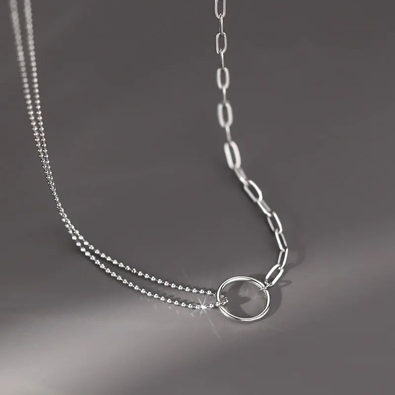 Une photo claire du collier pendentif en cercle à double couche en argent sterling 925, mettant en valeur son design asymétrique à double chaîne et son style minimaliste élégant.