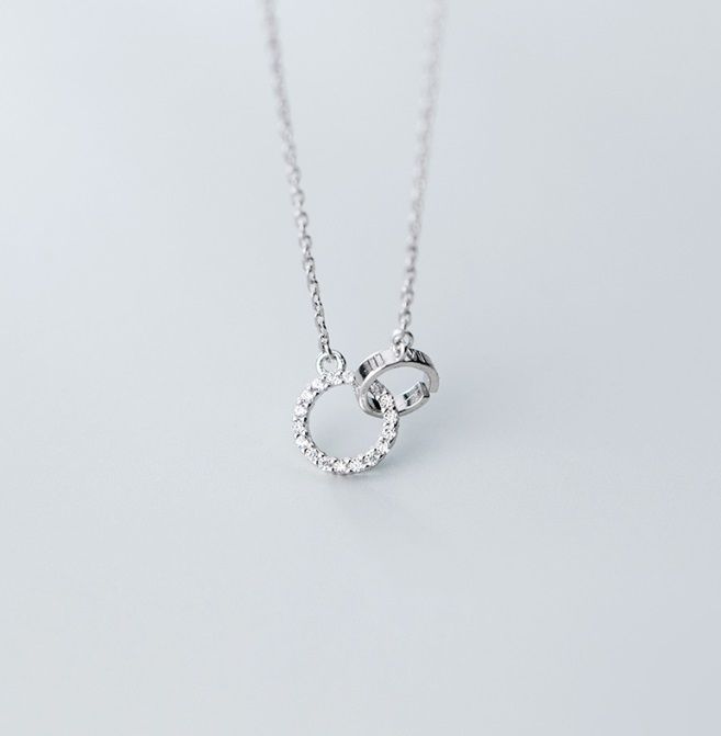 A close-up of the 925 sterling silver interlink circle necklace, showing the detailed craftsmanship of the two interlocking rings, one of which is elegantly paved with sparkling cubic zirconia stones.