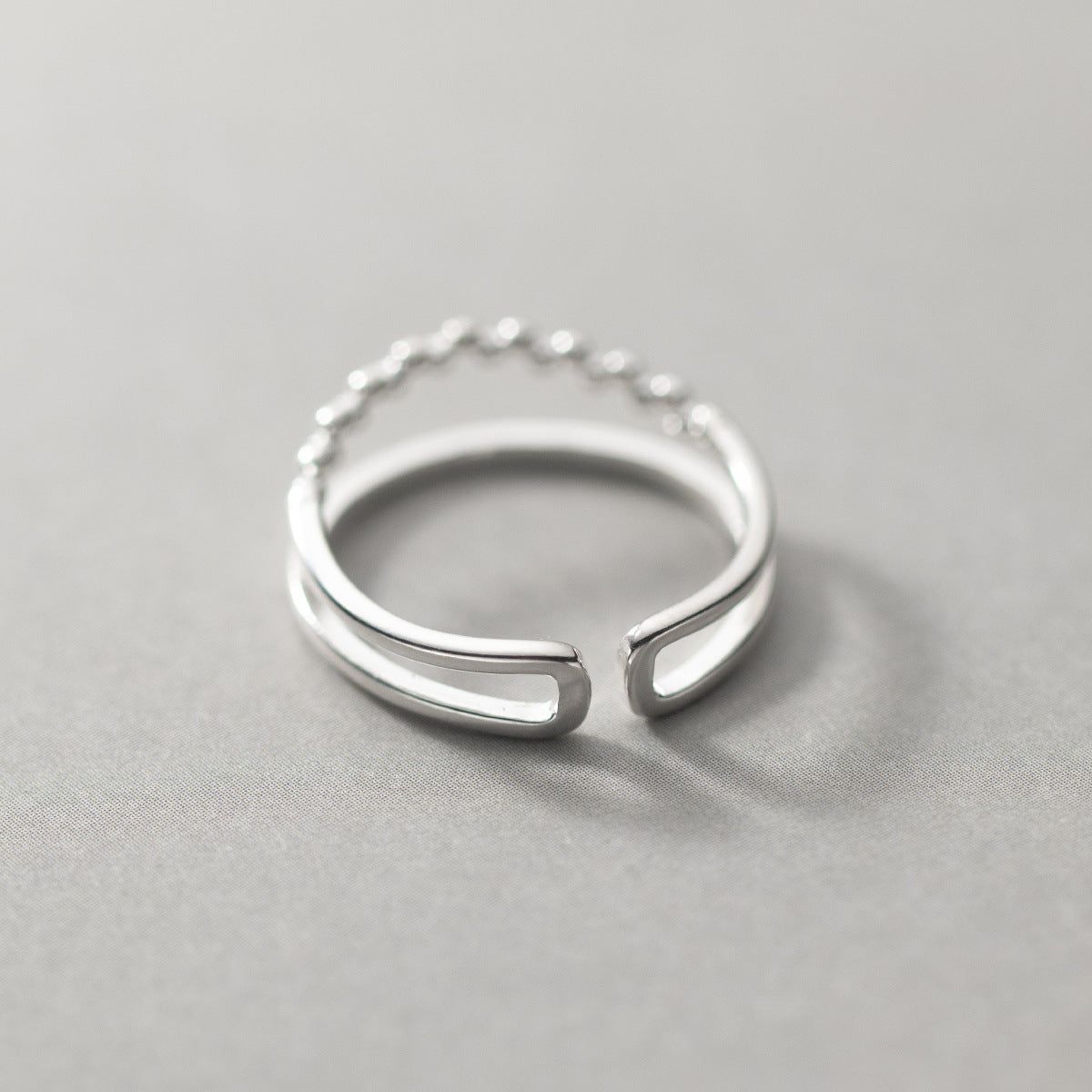 Un anillo abierto único de plata esterlina 925 del conjunto de Doble Capa con Cuentas Simples, mostrando su diseño de doble banda.