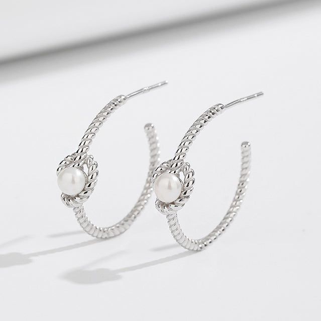 Un paio di orecchini a perno a forma di C in argento sterling 925 con nodo a corda su uno sfondo bianco pulito.
