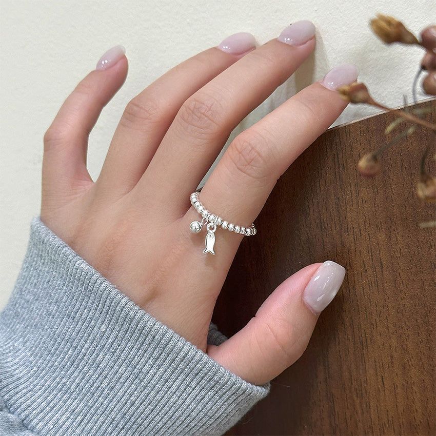 Modello che indossa l'anello minimalista con perline in argento sterling 925 per la vendita all'ingrosso, mostrando il delicato charm a forma di pesce e la sua elegante vestibilità per la moda quotidiana.