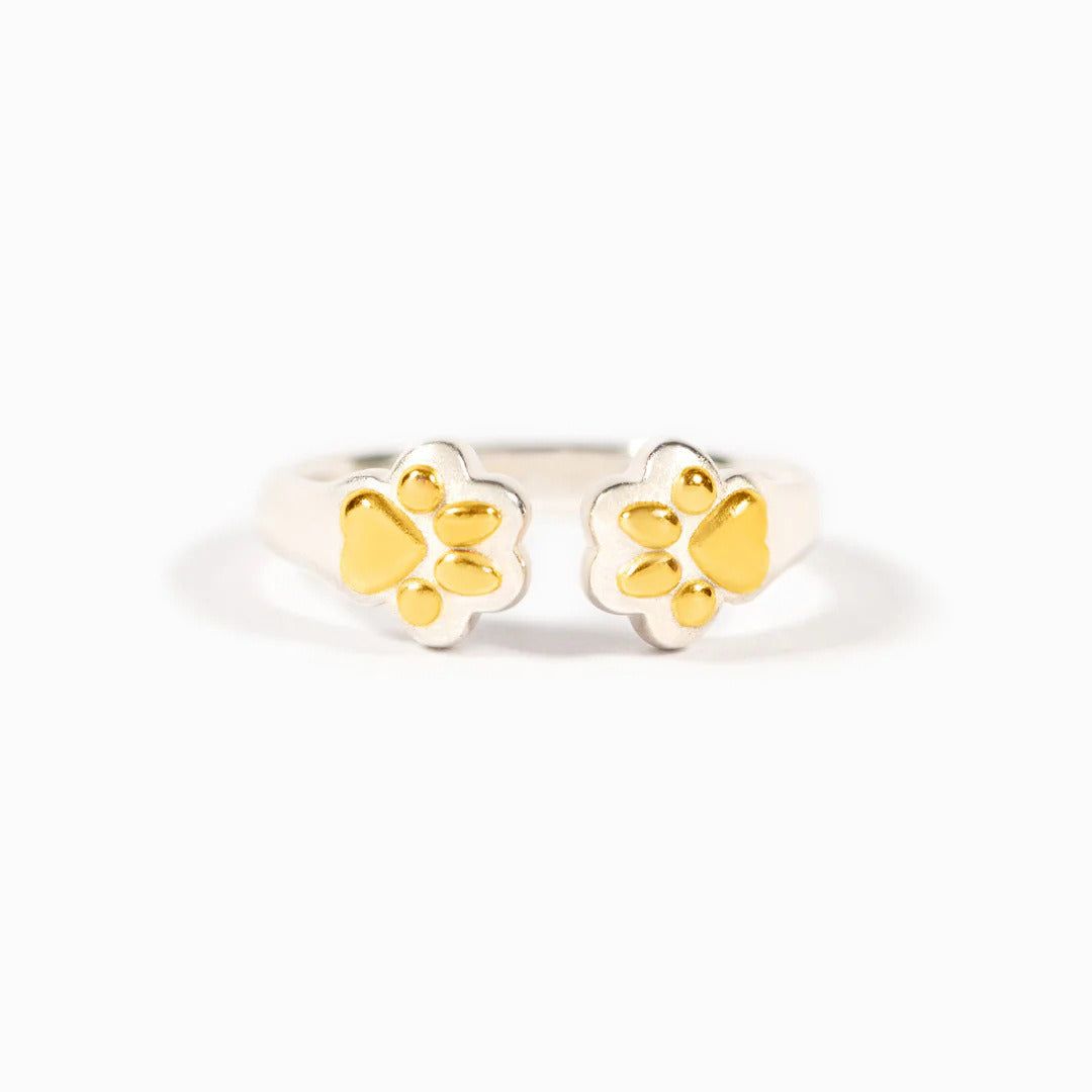 A close-up of the 925 sterling silver adjustable dog paw ring, highlighting the delicate gold-tone paw print details on the open band.