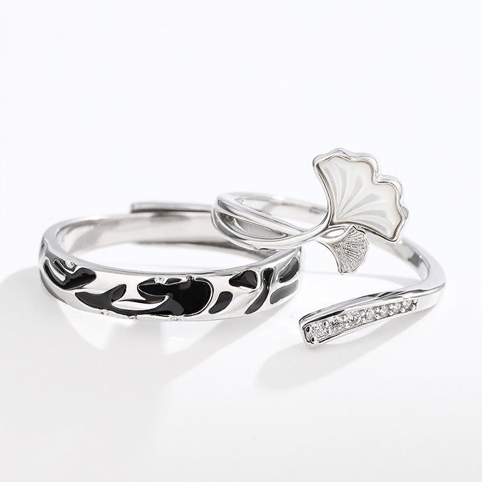 Une paire de bagues couples en argent sterling 925 avec un design complexe de feuille de ginkgo, symbolisant l'amour et l'endurance.