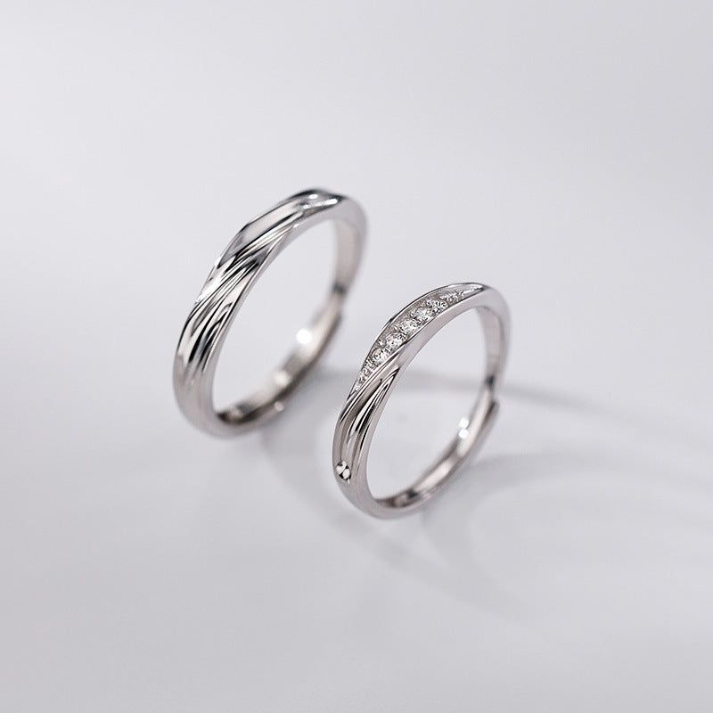 Elegant 925 sterling silver couple rings set, featuring one polished band and one band with cubic zirconia stones, on a white background.