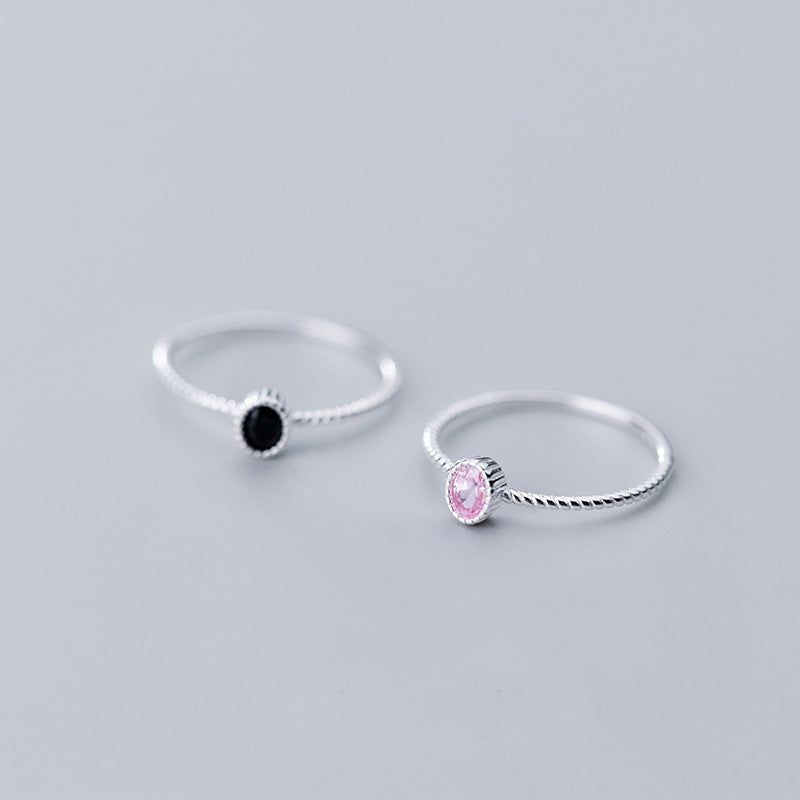 Ett set med två 925 sterling silverringar, en med en ensam svart kubisk zirkonia och den andra med en rosa, visade på en vit bakgrund.