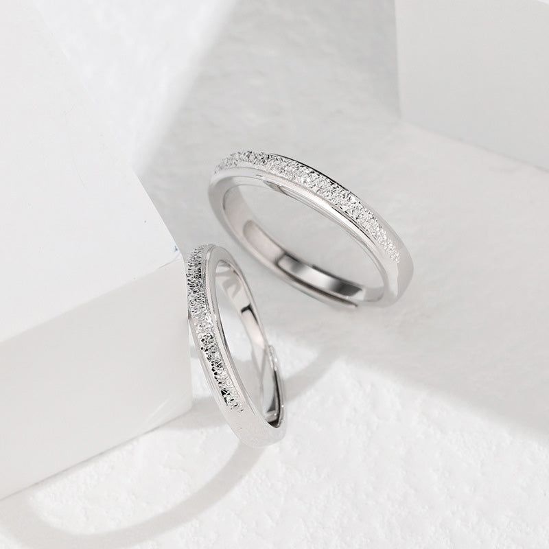 Un primo piano delle fedi nuziali regolabili Galaxy Bling in argento sterling 925, che mostrano le intricate incrostazioni di diamanti che brillano come una galassia.