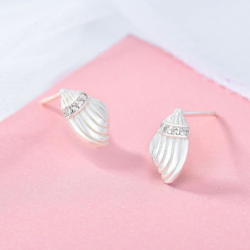 Un paio di orecchini a perno a forma di conchiglia in argento sterling 925, dettagliati in modo intricato e adornati con pietre chiare scintillanti, esposti su uno sfondo bianco pulito.