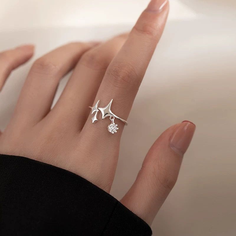 Närbild av en ring i 925 sterling silver med en minimalistisk fyrpunktsstjärna hängande med en glittrande, hängande kubisk zirkonia.