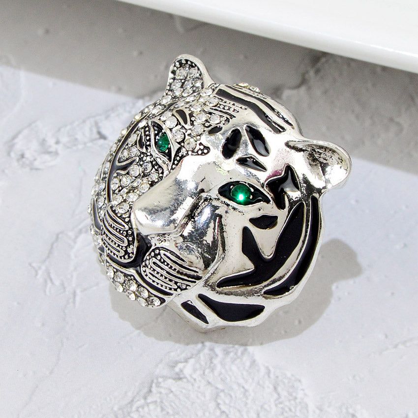 Een gedetailleerde close-up van een luxe zilververgulde tijgerkop broche, ingewikkeld versierd met sprankelende heldere rhinestones en opvallende groene edelsteenogen.