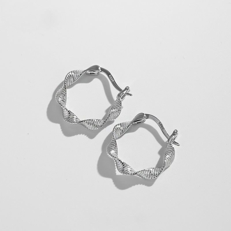 Een paar S925 sterling zilveren Möbius gedraaide hoepel oorbellen met een textuurontwerp, getoond tegen een witte achtergrond.