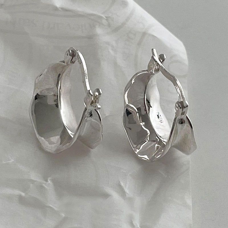 Un paio di orecchini a cerchio larghi a onda in argento sterling 925 che mostrano il loro design ondulato unico ed elegante su uno sfondo pulito.